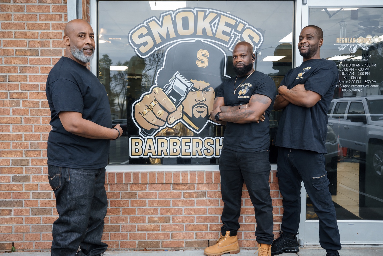 Scootz Da Barber, Owner Smoke, and Reggie standing outside Smoke's Barbershop